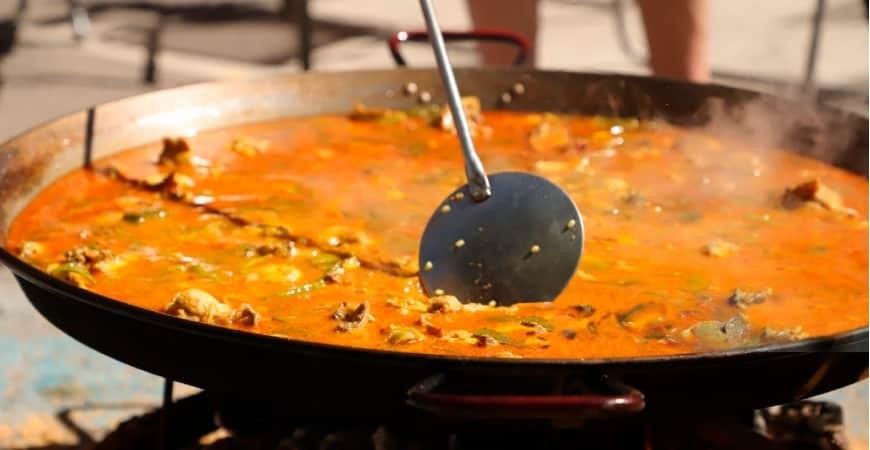 How does altitude and climate affect the cooking of paella?